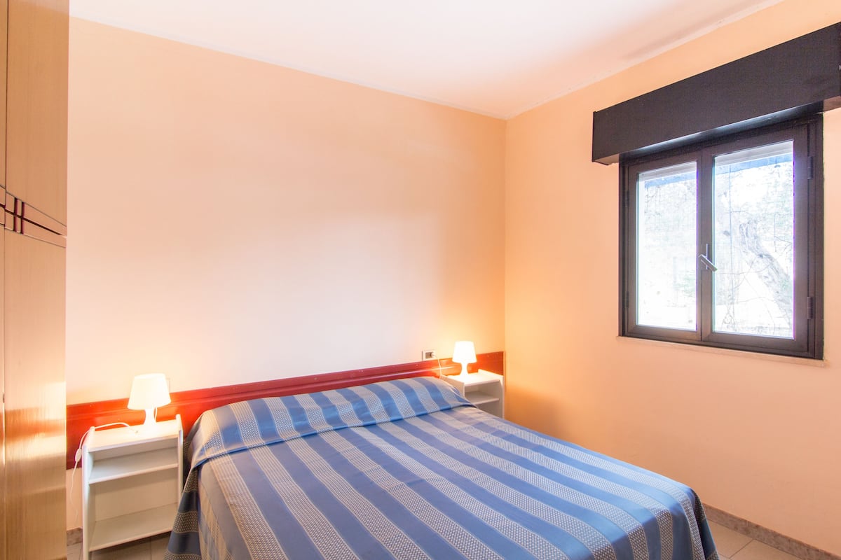A bedroom with a bed, nightstands, and a window.
