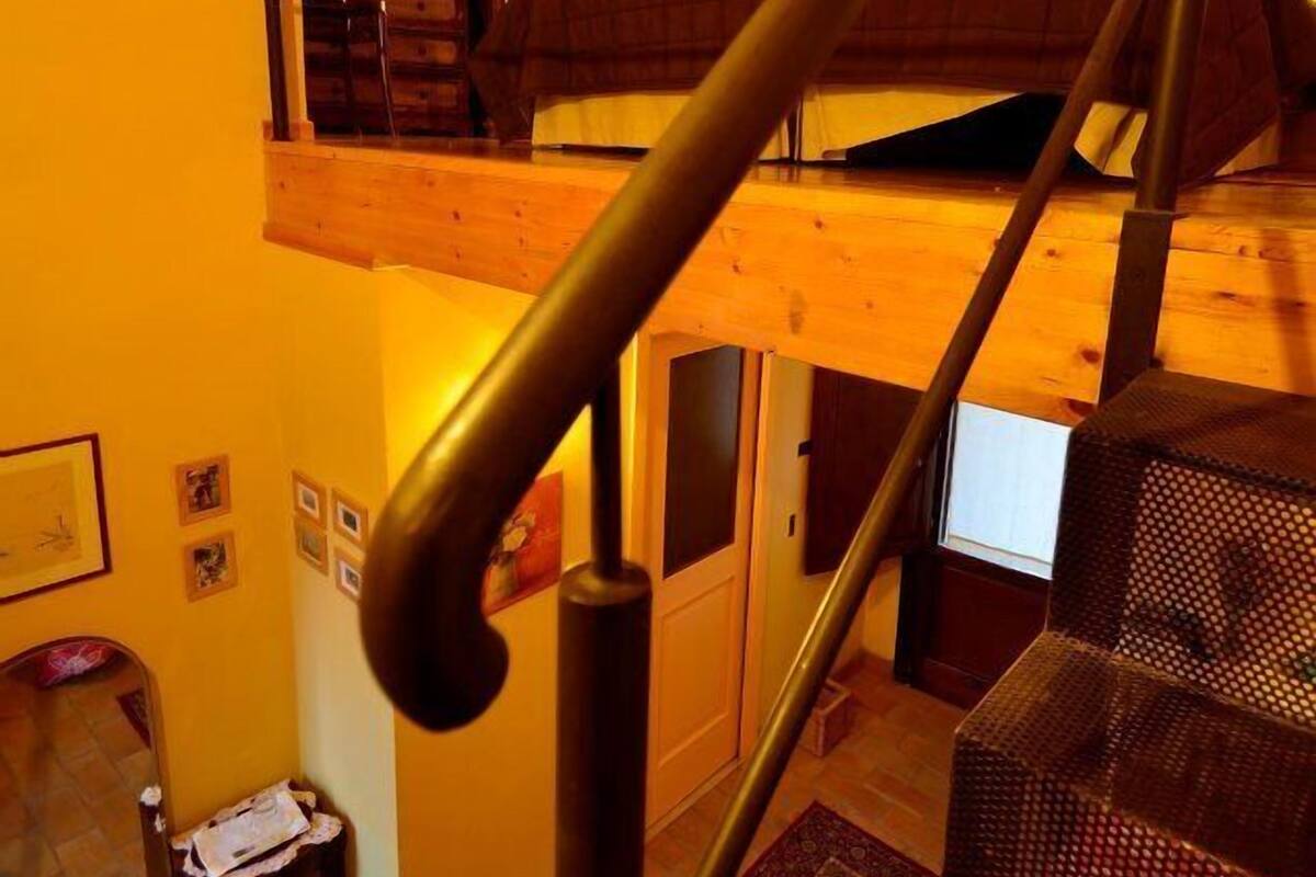 Un escalier avec une rampe en bois menant à une chambre située en mezzanine.