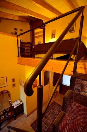Uma escada com corrimão de madeira leva a um quarto no mezanino.