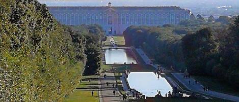 A long, straight pathway with a water feature and a large building in the background.