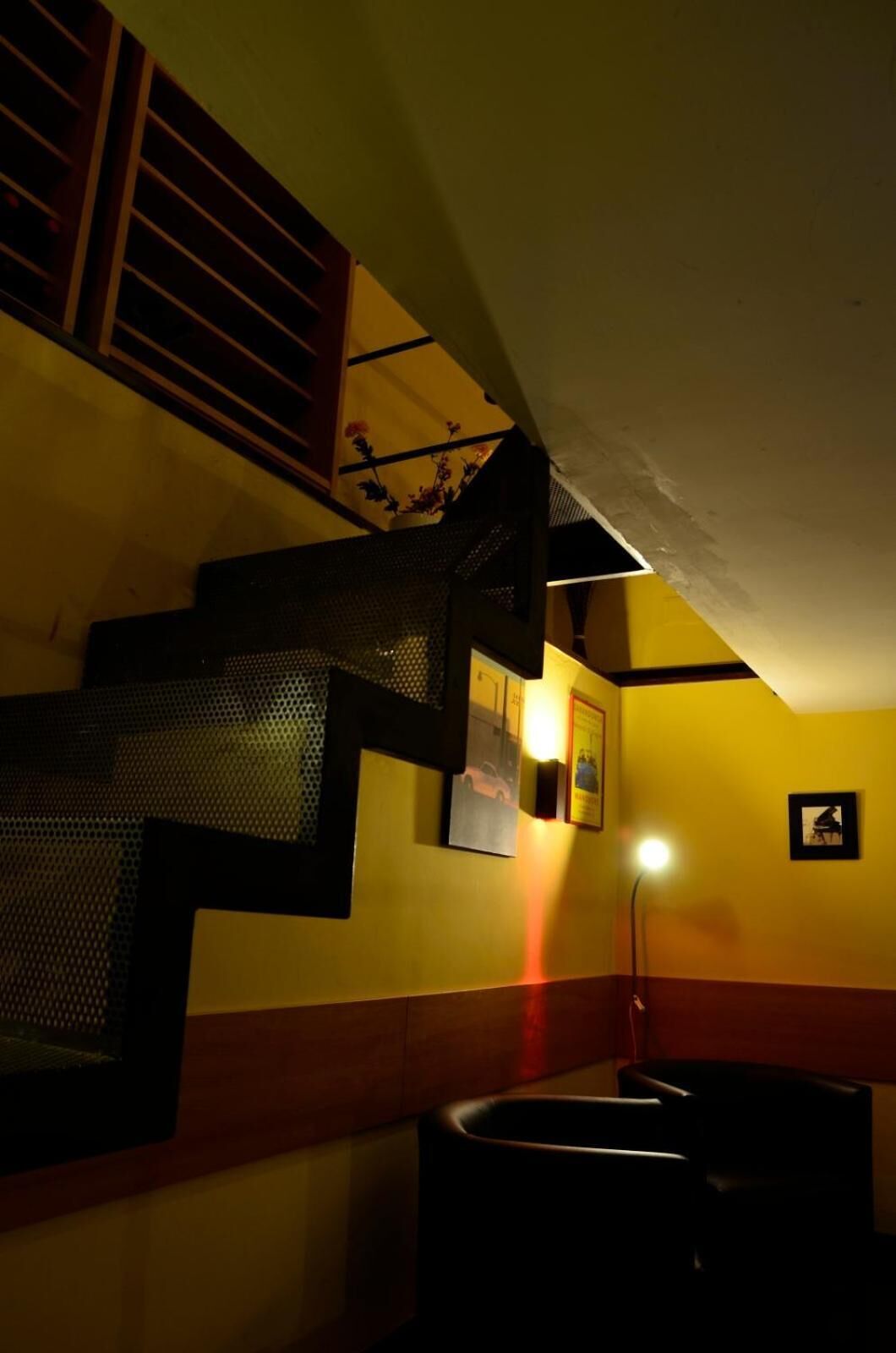 A staircase with a mesh railing, a wall-mounted light, and a framed picture.