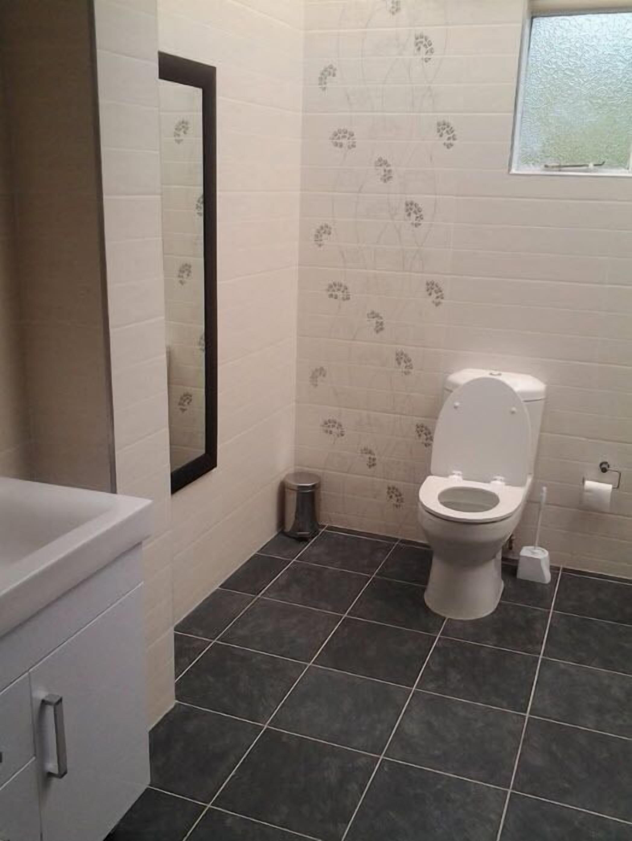 A bathroom with a toilet, a bidet, and a small trash bin.