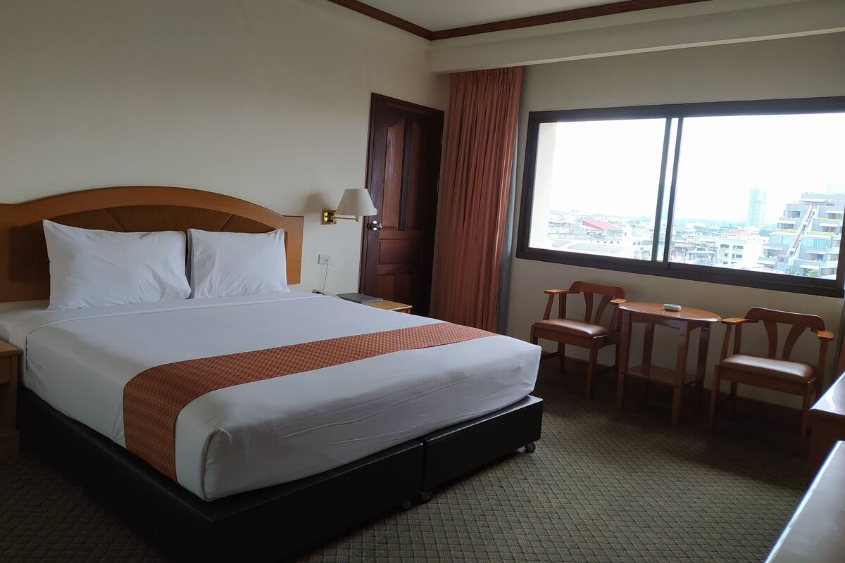 A hotel room with a large bed, a desk, and a chair.