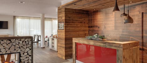 Cozinha moderna com parede de destaque em madeira, bancada vermelha e lareira.