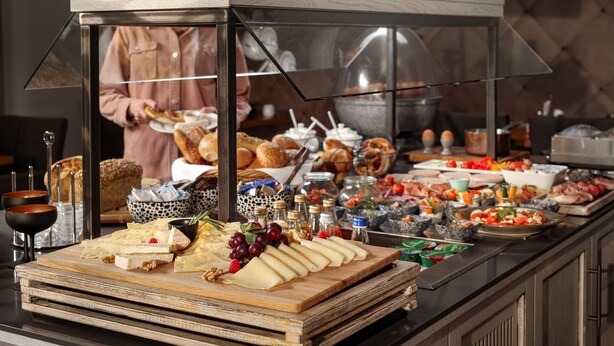 A buffet with various cheeses, fruits, and breads.