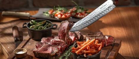 A wooden cutting board with sliced steak, fries, and a small bowl of seasoning.