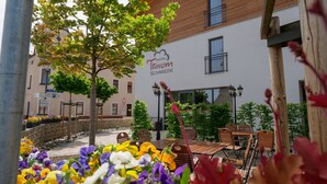 A hotel named 'Hotel Truem' with outdoor seating and flower beds.