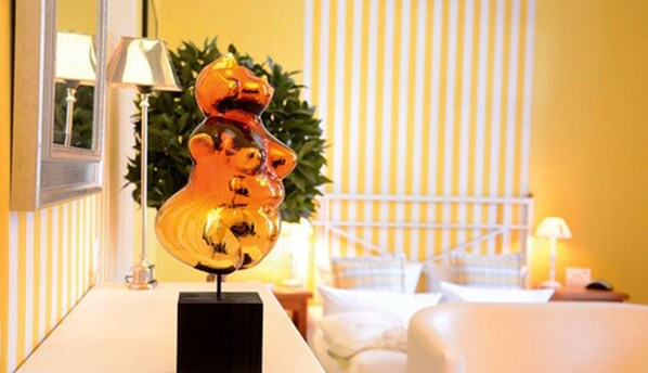 A hotel room with a bed, a nightstand, a lamp, and a decorative glass sculpture on a black base.
