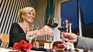 Une table à manger avec des verres à vin, une bougie et une rose.
