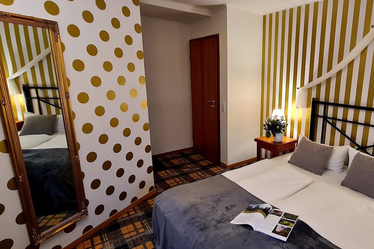 Ein Hotelzimmer mit einem Bett, einem Nachttisch mit Lampe, einem Spiegel und einer Tür.