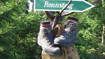 Wanderschuhe auf einem Rucksack, mit einem Wegweiser, der 'Rennsteg' und '3,0 km' anzeigt.