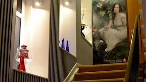 Un escalier aux murs rayés et une affiche représentant une femme en robe blanche.