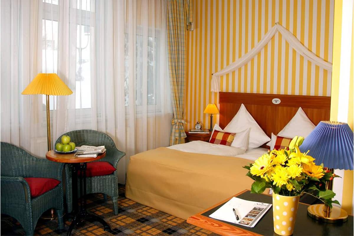 Ein Hotelzimmer mit Bett, Stuhl, Tisch und Fenster.