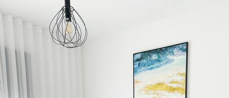 Et hotelværelse med to senge, hvidt sengetøj, en træsenggavl, et billede på væggen og en moderne lampe.