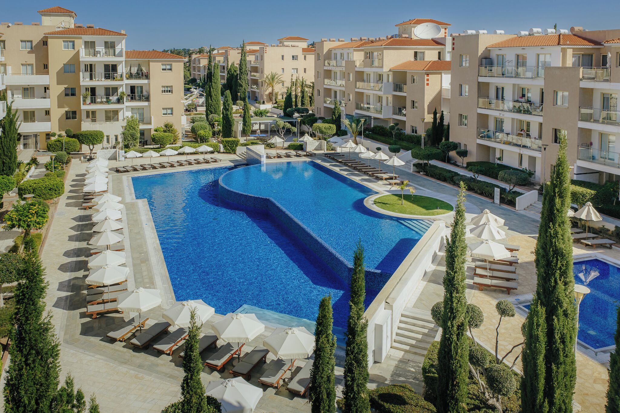 A hotel with a large swimming pool, multiple balconies, and lush landscaping.