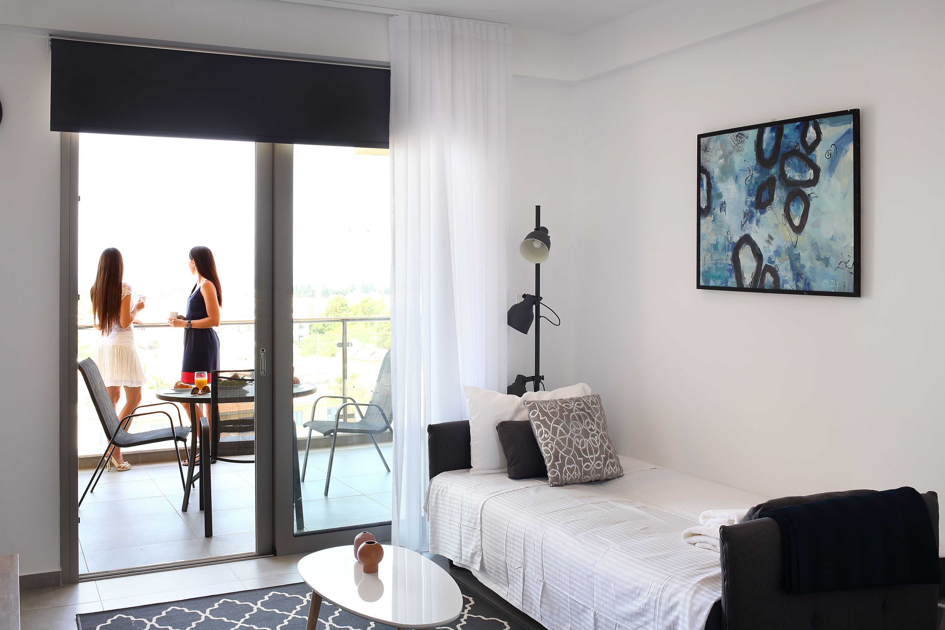 Una camera da letto moderna con un letto, un quadro e un balcone con due persone.