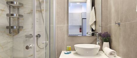 Un baño moderno con ducha envuelta en vidrio, un lavamanos blanco y un espejo sobre el mueble de tocador.