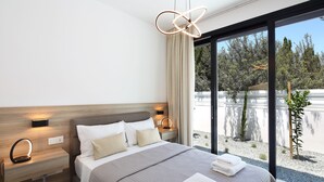 Una habitación de hotel moderna con una cama grande, mesitas de noche y vistas al exterior.