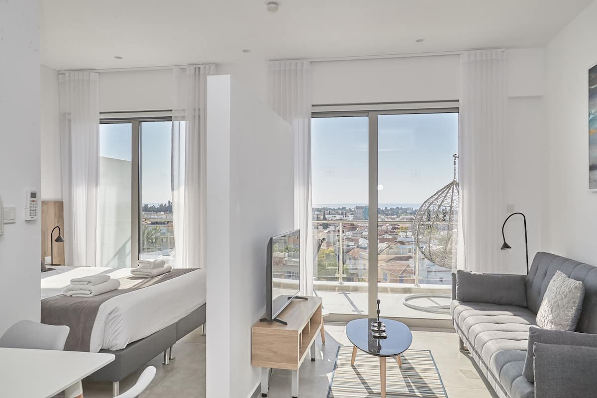 Una habitación de hotel moderna con una cama, un sofá, una mesita y vistas a la ciudad.