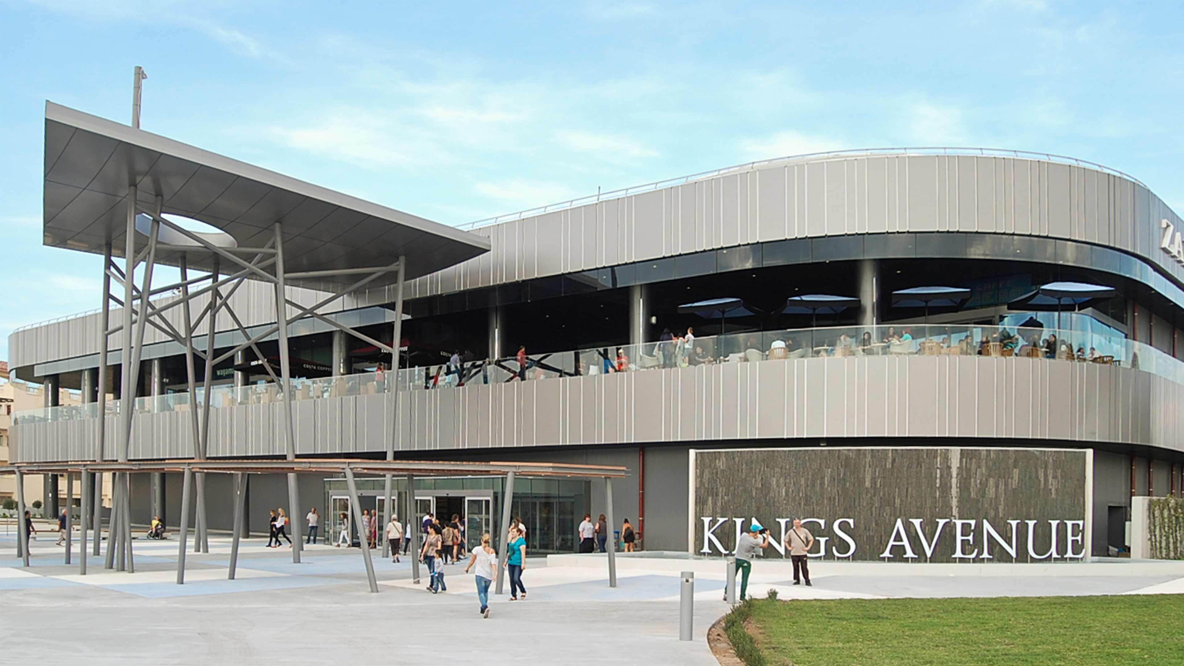 A modern building with a curved facade and a prominent sign reading "Kings Avenue".