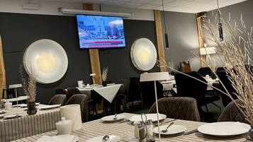 A conference room with a large table set for a meeting, a television screen displaying a news program, and a modern interior design.