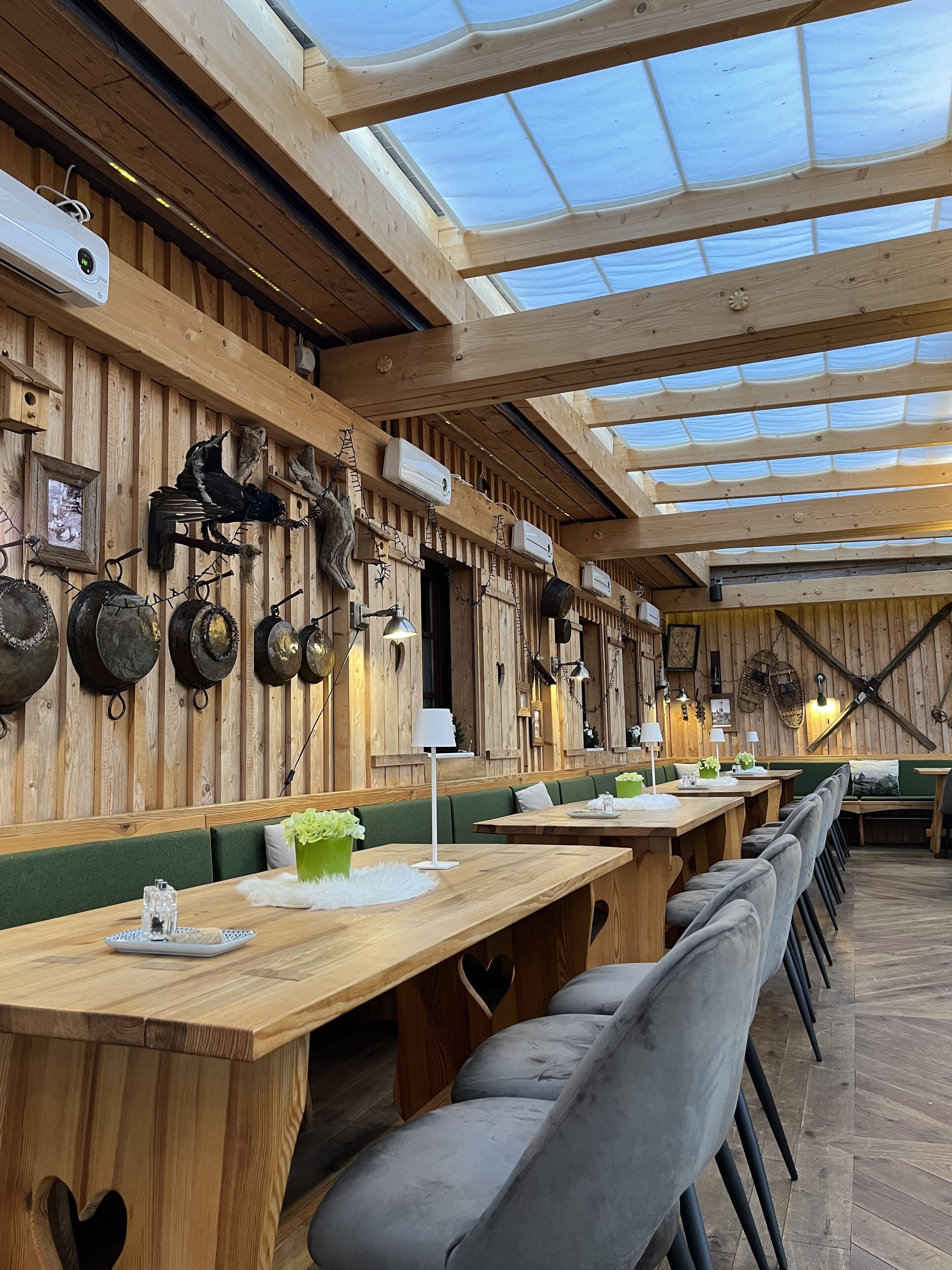 Un restaurante con paredes de madera, ollas colgantes y techo de cristal.