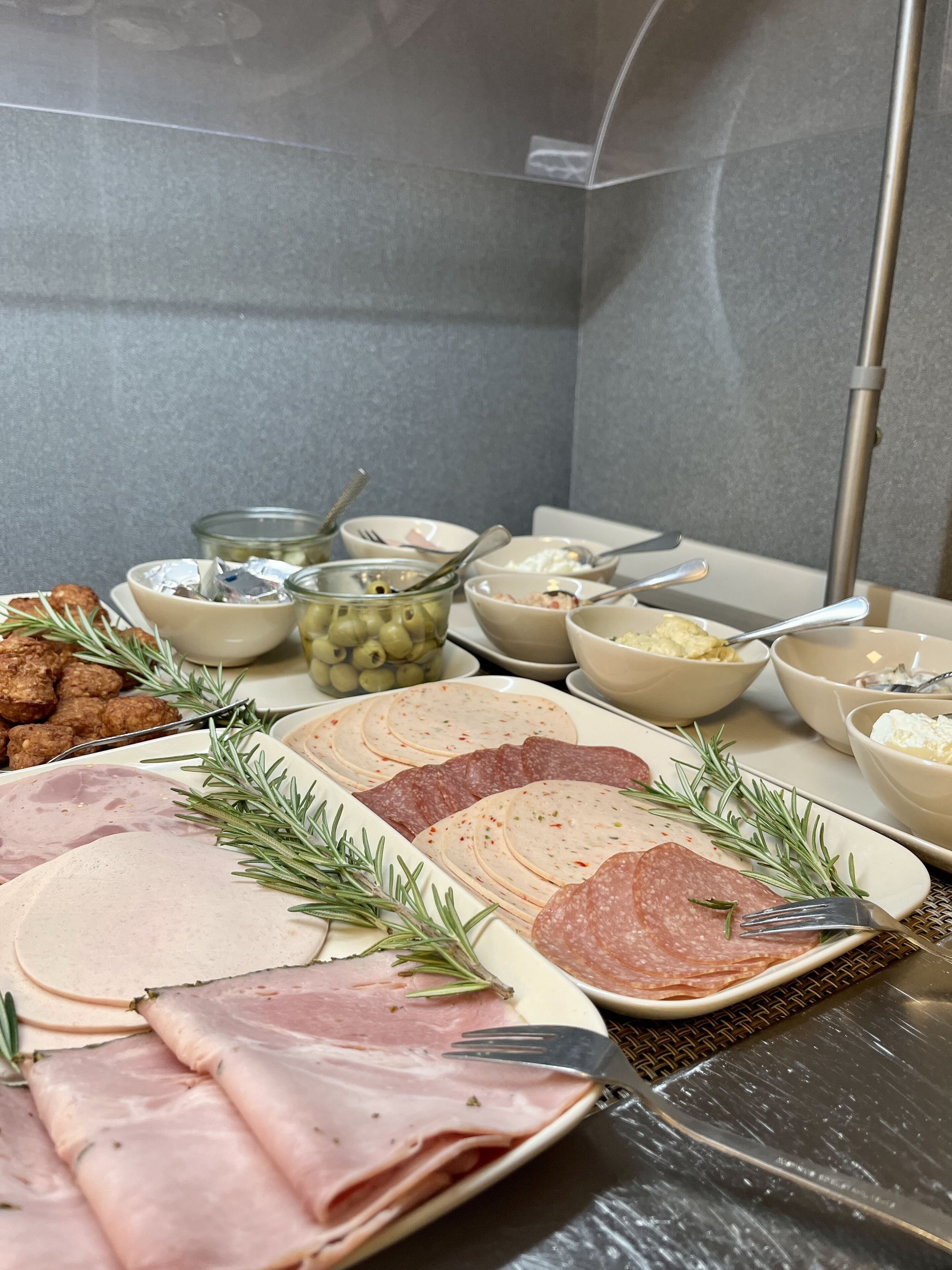 Un bufé con diferentes carnes, quesos y aceitunas.