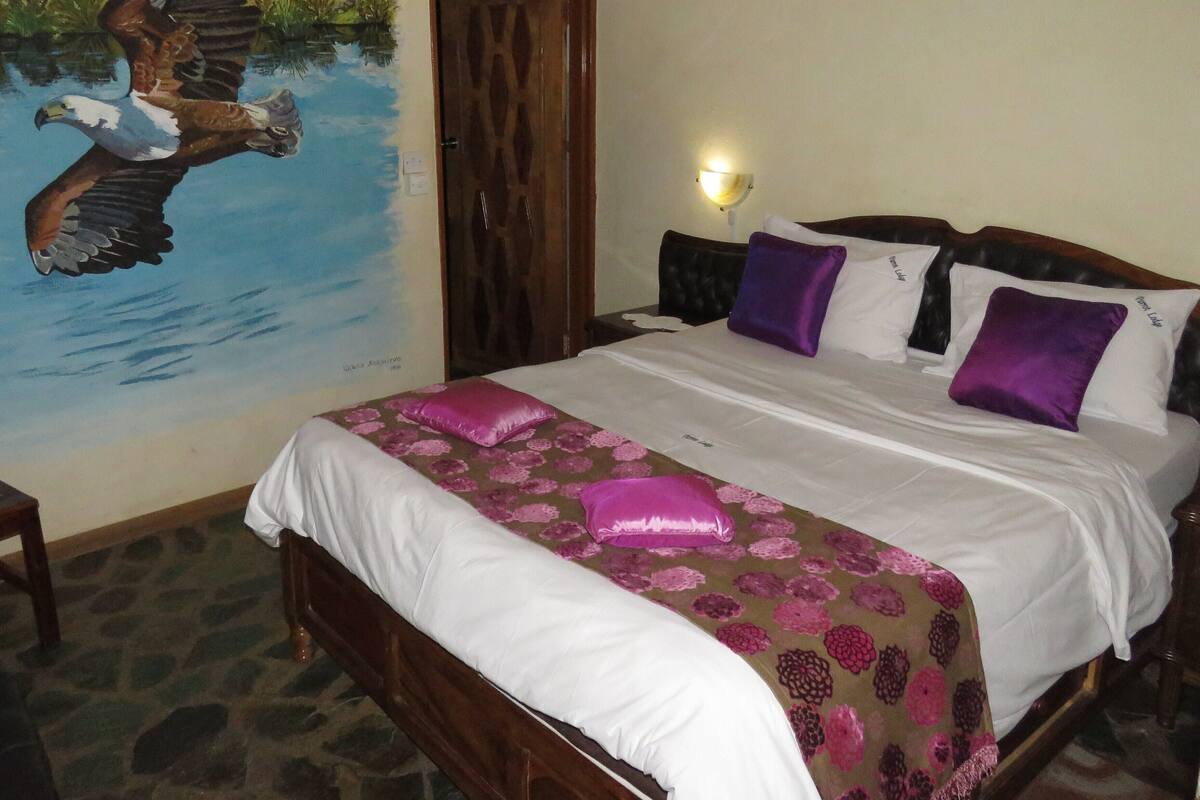 A bedroom with a bed, a ceiling fan, a wall mural of an eagle, and a nightlight.
