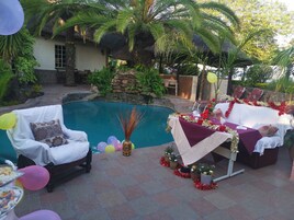 Zona junto a la piscina con área de comedor, sillas y mesa decorada.