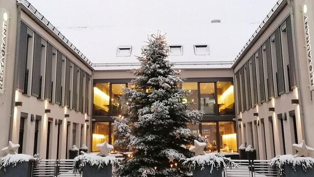 Un árbol de Navidad cubierto de nieve en el centro de un edificio de dos alas, cada ala con un letrero que dice "RESTAURANT".
