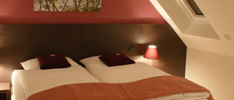 A bedroom with a large bed, a nightstand, a lamp, and a painting on the wall.