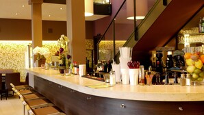 Zona de bar con taburetes, una barra con diversos artículos y una escalera al fondo.