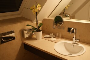 A bathroom with a white sink, a mirror, a potted orchid, and a towel rack. - KH Hotel (Geisenfeld)