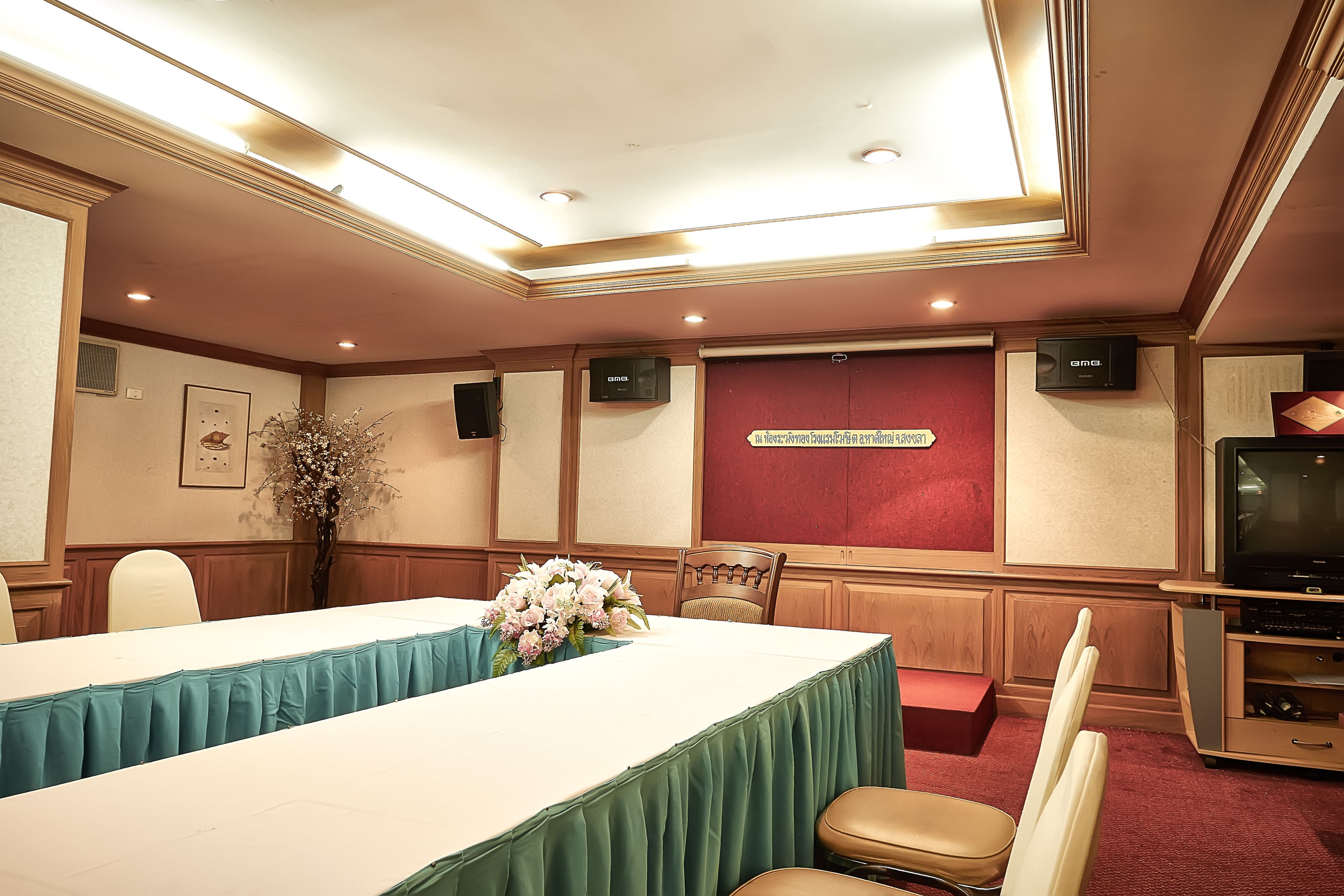 A conference room with a long table, chairs, a television, and a floral arrangement.