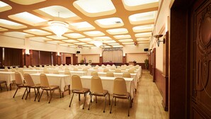 A banquet hall with long tables, chairs, and a decorative ceiling.
