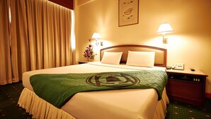 A hotel room with a large bed, two bedside lamps, a nightstand, and a framed picture on the wall.