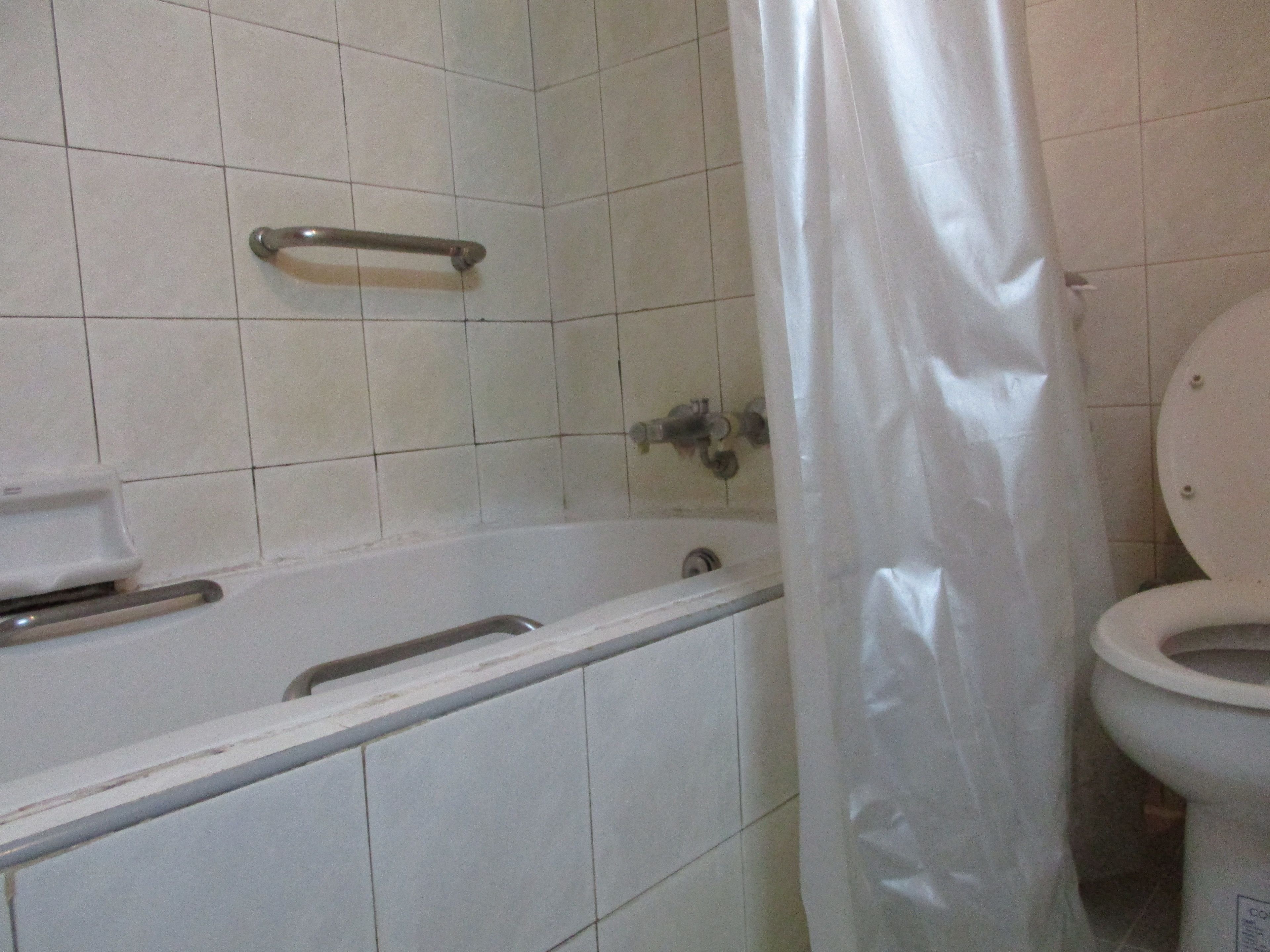 A bathroom with a bathtub, toilet, and a shower curtain.