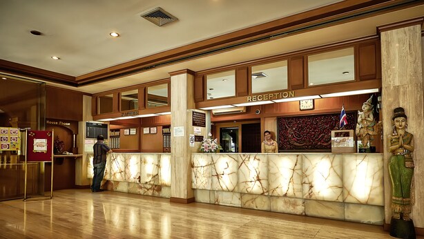 A hotel reception area with a marble counter, a reception desk, a 'House Phone' sign, and a statue.