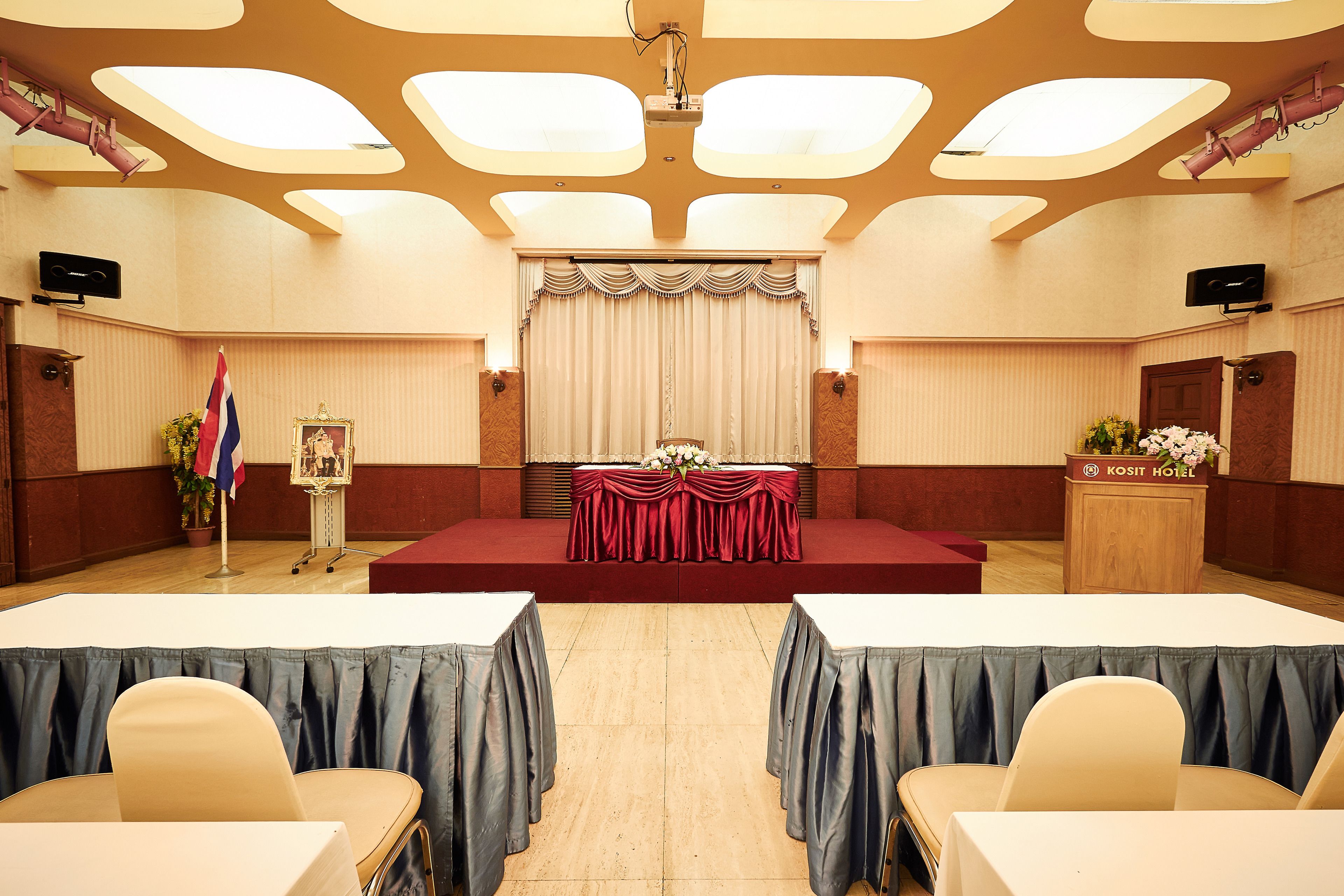 A conference room with a stage, tables, chairs, and a podium.