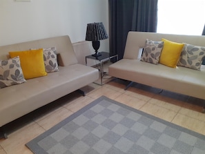 A living room with two sofas, a small table, a lamp, and a checkered rug.
