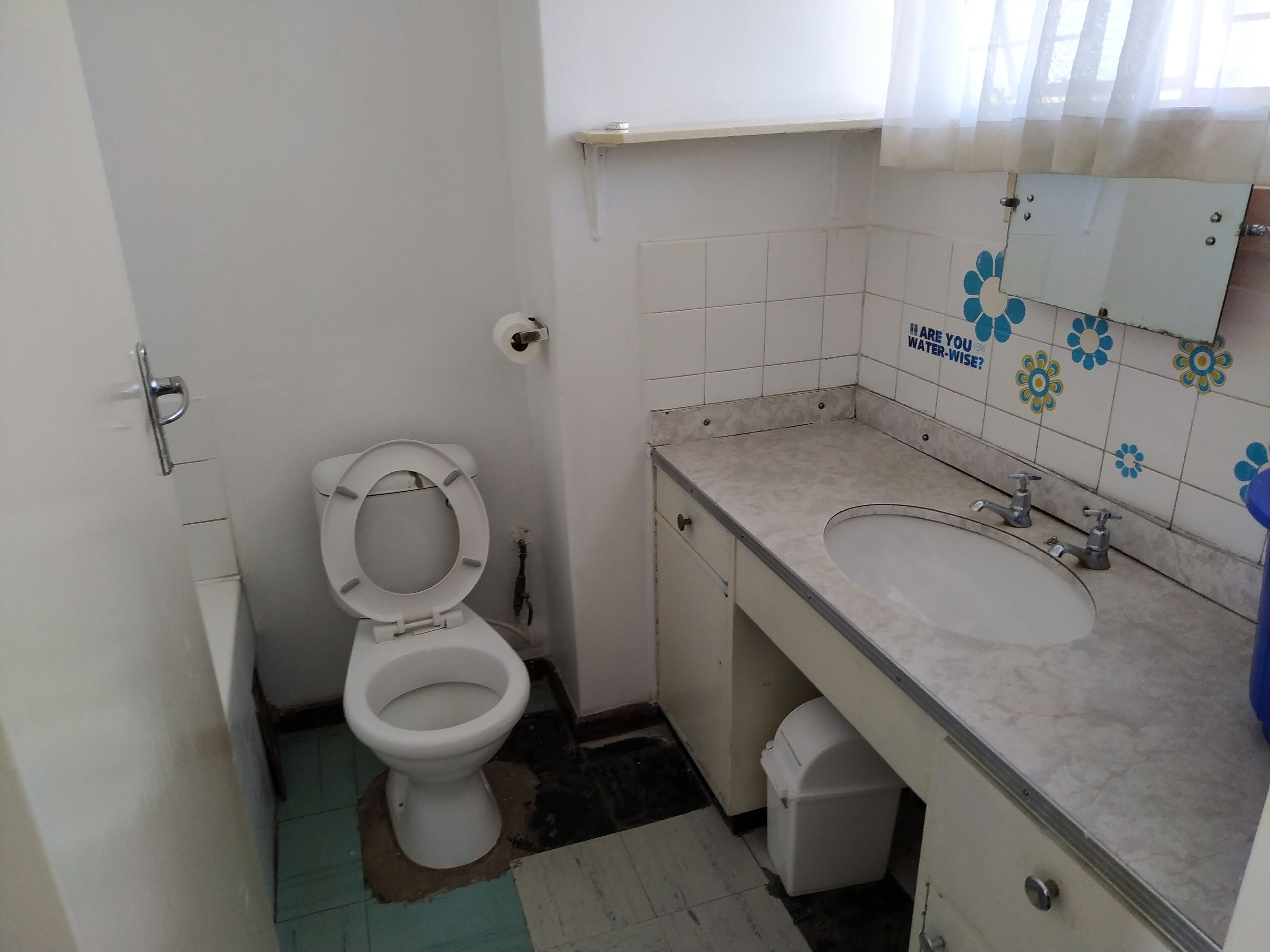 A small bathroom with a toilet, sink, and a mirror.