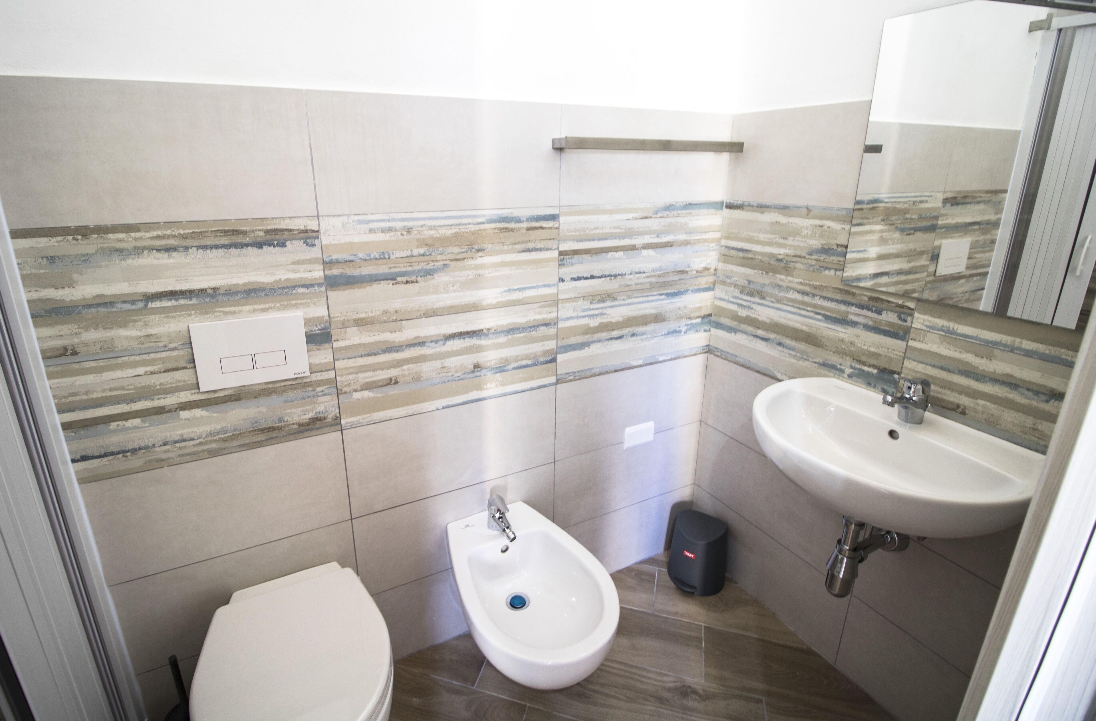 A modern bathroom with a bidet, a sink, and a mirror.