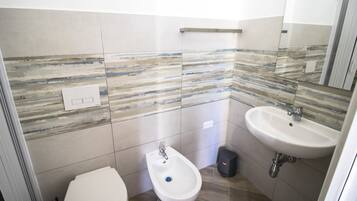 A modern bathroom with a bidet, a sink, and a mirror.