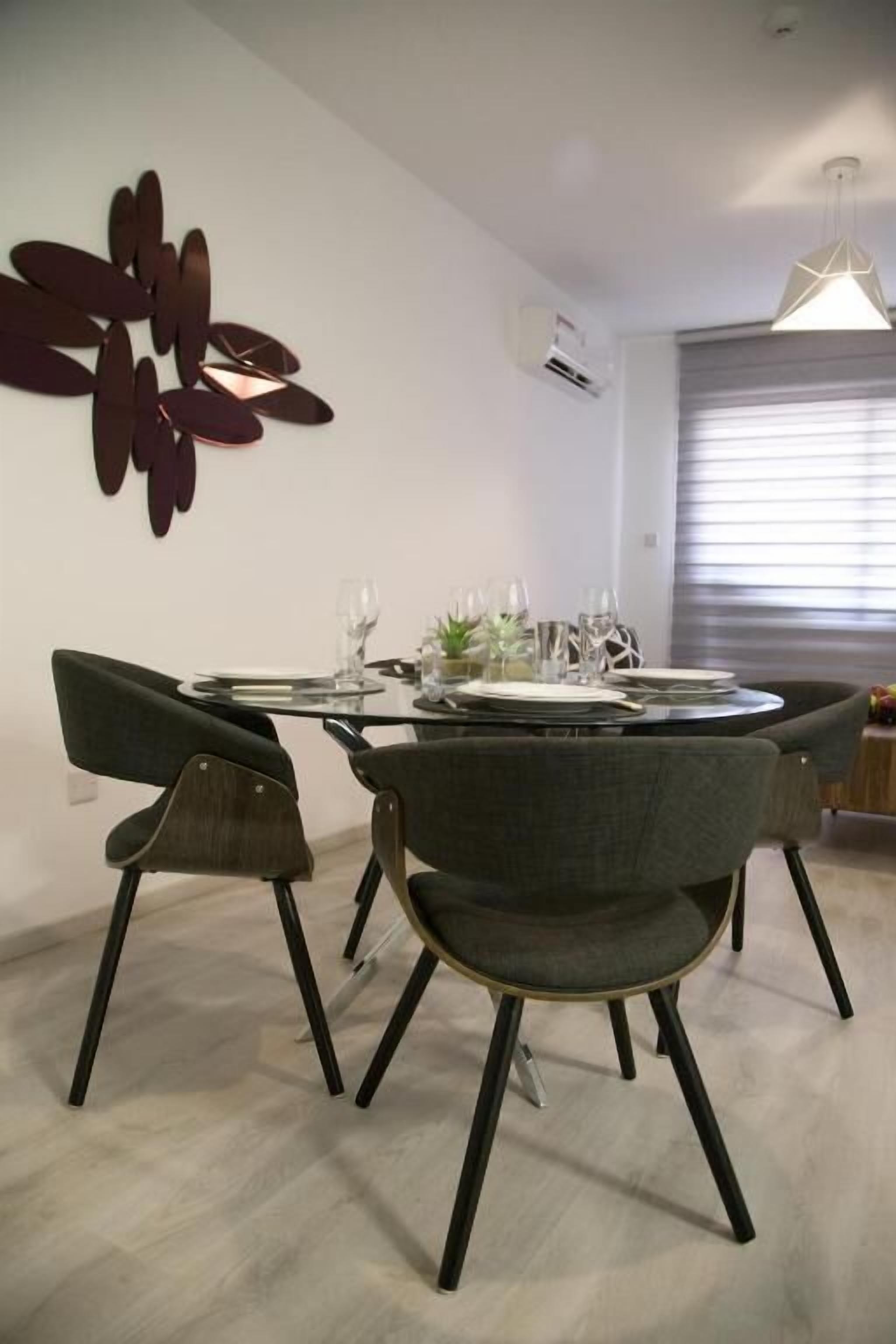 A dining area with a round table set for four, surrounded by modern chairs.