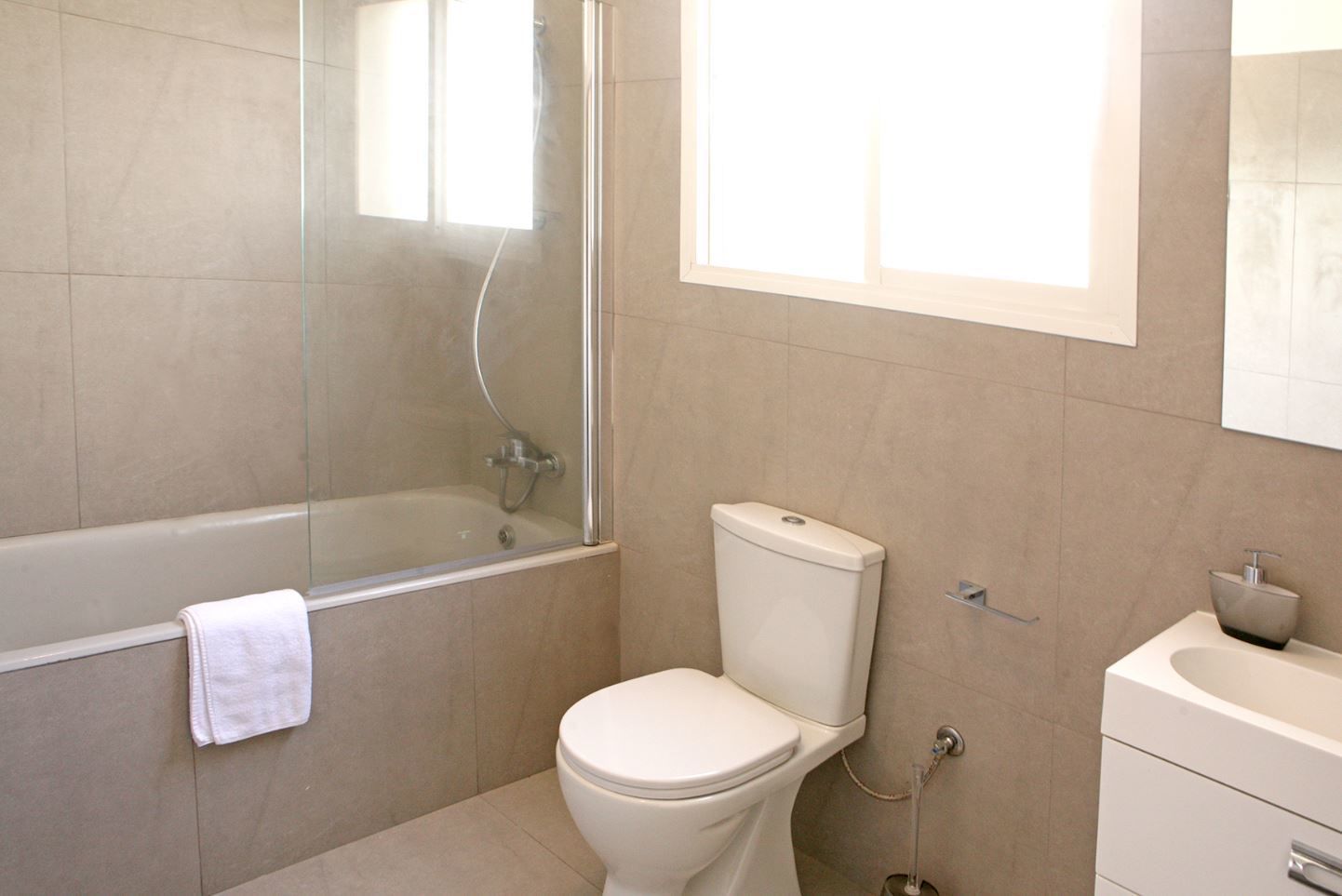 A bathroom with a glass-enclosed shower, a toilet, and a sink.