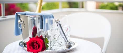 Una mesa con una bandeja de plata que sostiene una botella de champán, copas y una rosa roja.