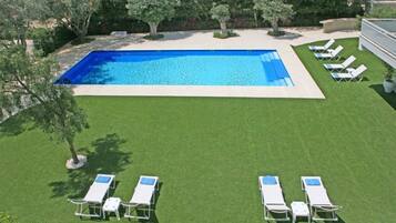 Una piscina al aire libre, sillones reclinables de piscina