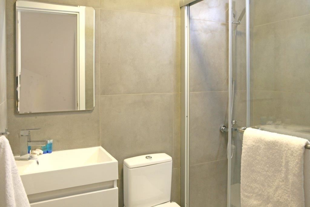 A bathroom with a white sink, a toilet, and a glass shower enclosure.