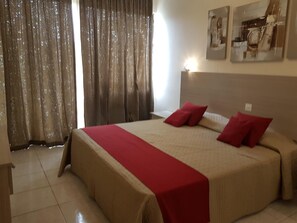 A bedroom with a large bed, red pillows, and a red bedspread.