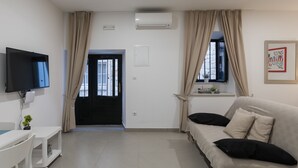 A modern living room with a sofa, TV, and a door leading outside. - Apartments Ivana (Dubrovnik)